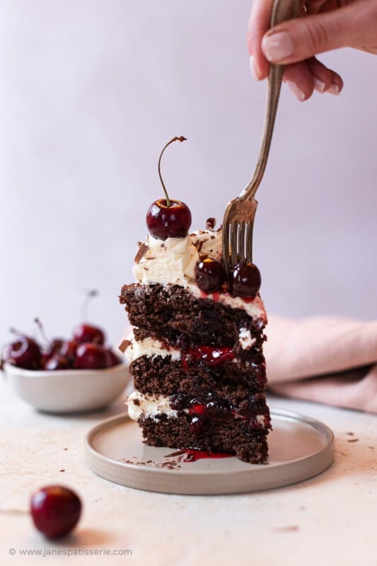 A fork gliding into a slice of black forest fudge cake