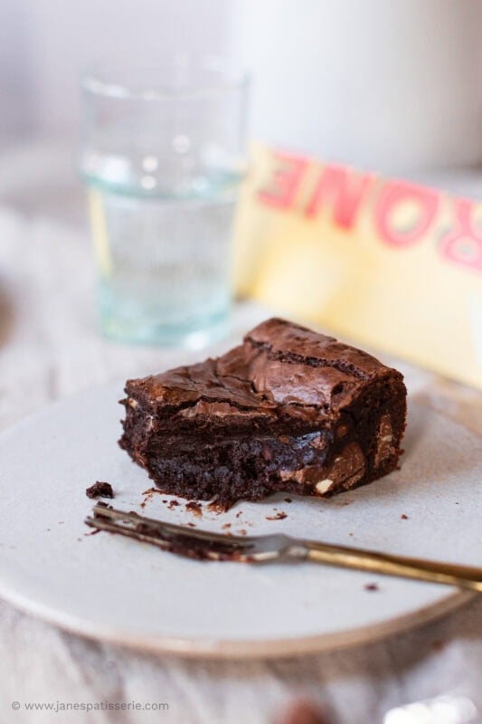A fork and a plate with a toblerone brownie on top, bite missing