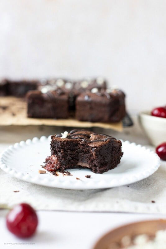 A bite taken from a black forest brownie on a plate.