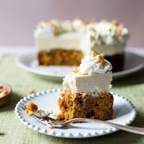 A bite missing from a slice of carrot cake cheesecake