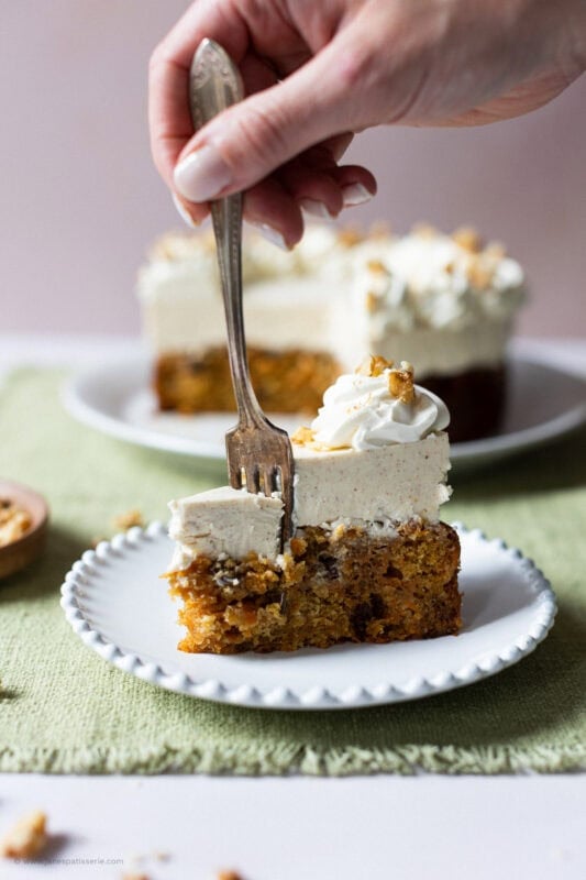 A fork sliding into a carrot cake cheesecake slice