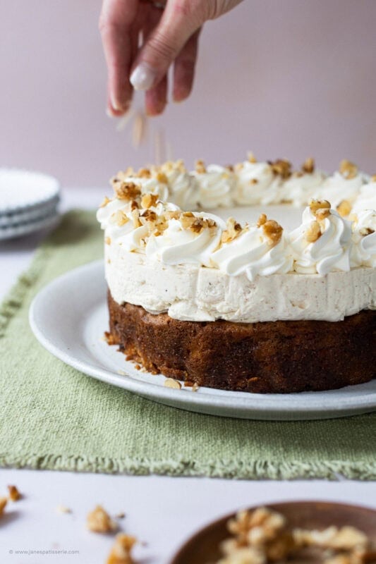A hand decorating a carrot cake cheesecake