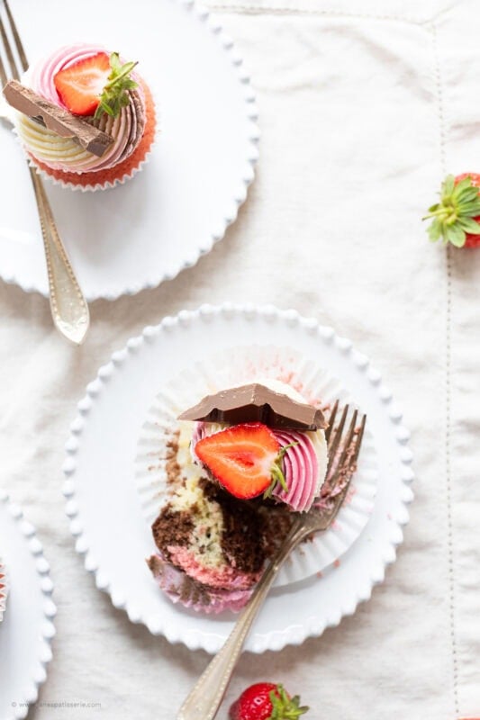 A half eaten Neapolitan Cupcake on a white plate
