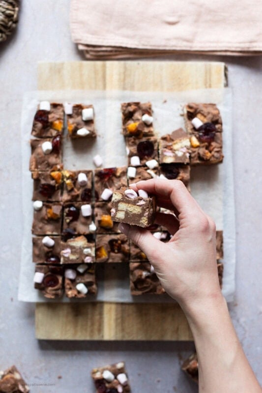 A hand holding a piece of Rocky Road Fudge above the rest