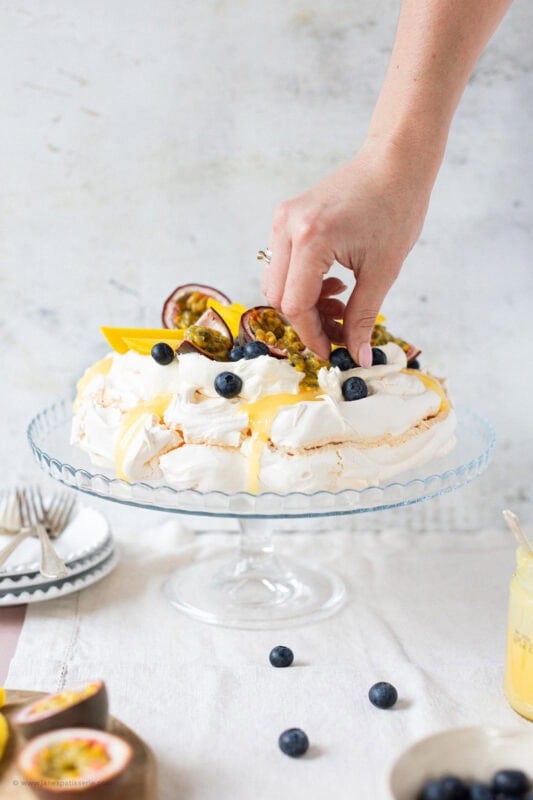 A hand placing the final decorations of a Spring Pavlova