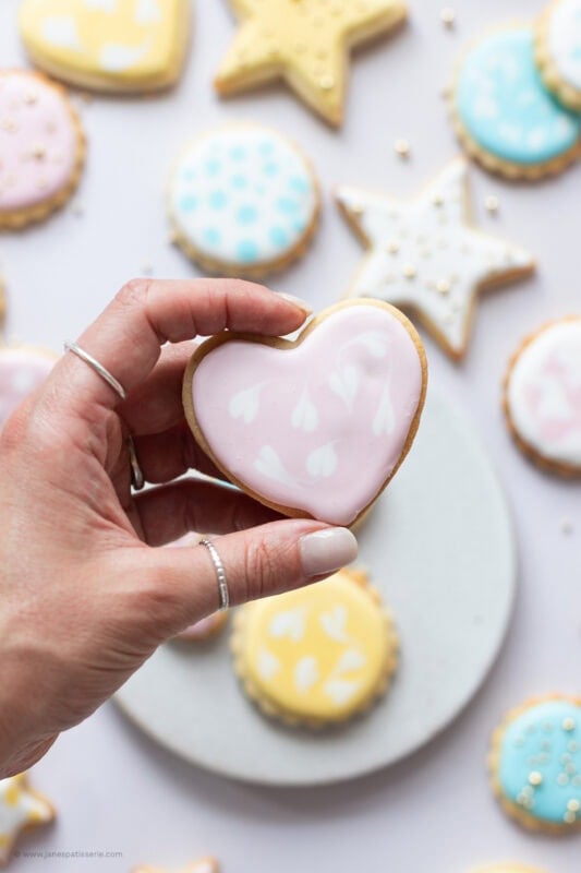 A hand holding a heart shaped Sugar Cookie