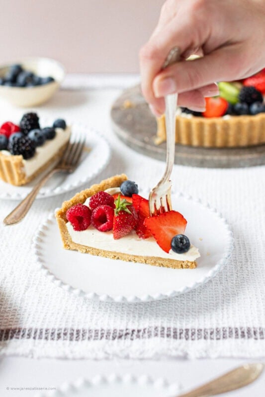 A fork picking up fruit from the top of a slice of Easy Fruit Tart
