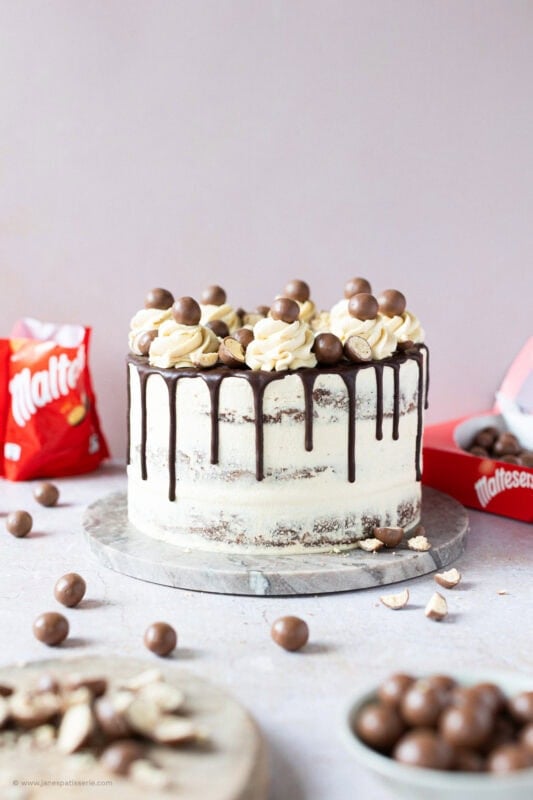 A Malteser Drip Cake surrounded by Malteser bags