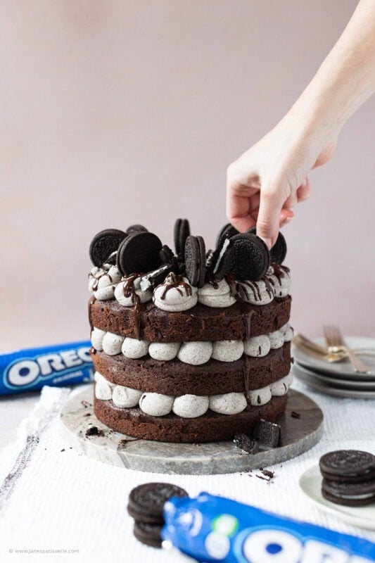 A hand decorating a finished Oreo Cake
