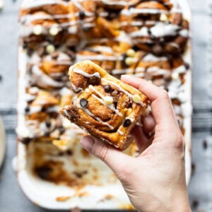 A hand holding a Sticky Chocolate Sweet Roll above the tray