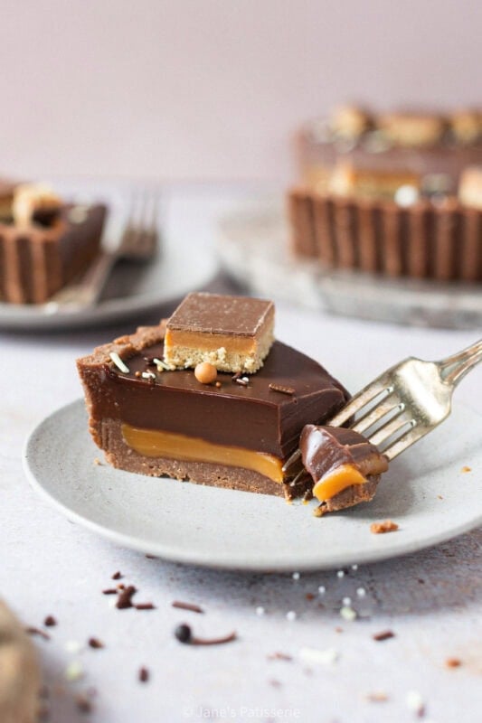 A fork cutting into a slice of Billionaires Tart on a plate