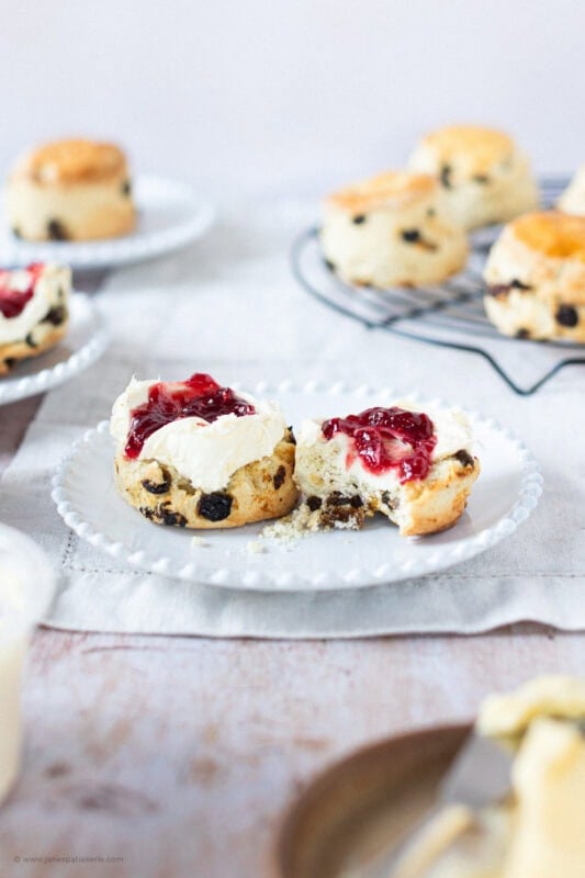 A bite taken from a Fruit Scone with jam and clotted cream