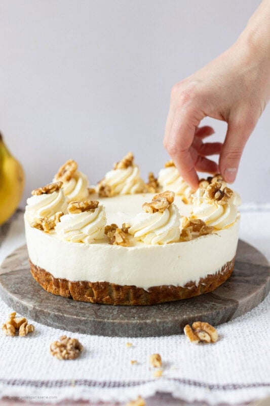 A hand decorating a Banana Bread Cheesecake