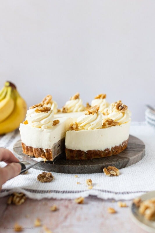 A slice being taken from a whole Banana Bread Cheesecake
