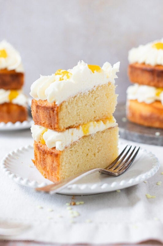 A slice of Lemon Celebration Cake on a white plate with a fork