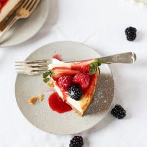 A bite taken from a slice of New York Cheesecake on a grey plate