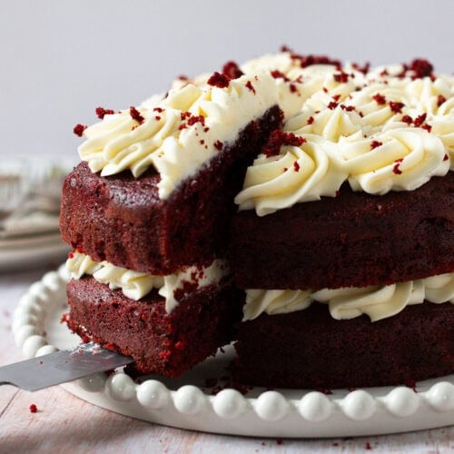 A slice of Red velvet cake being taken from a finished cake